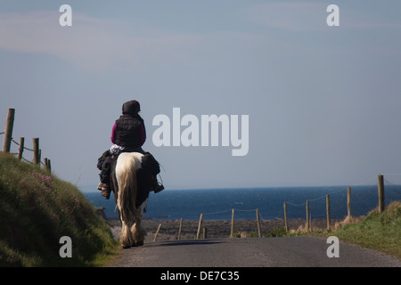 Two women riding horses on the road in Ireland. Stock Photo
