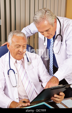 Two doctors talking about a checklist in a hospital office Stock Photo