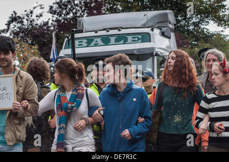 Balcombe, West Sussex, UK. 12th September 2013.  Environmentalists link arms and walk in front of Police officers escorting lorry to Quadrilla site.... The anti fracking environmentalists are protesting against test drilling by Cuadrilla on the site in West Sussex that could lead to the controversial fracking process. Credit:  David Burr/Alamy Live News Stock Photo