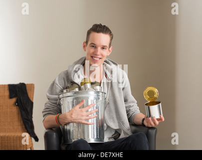 Eco friendly young man holding trash can, recycling metal tins Stock Photo