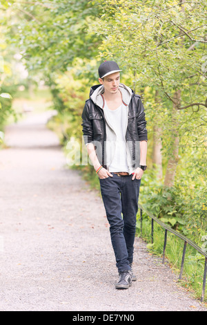 Young man walking by himself on footpath in a park Stock Photo