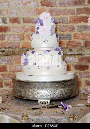 Wedding cake and knife on table at reception showing details of purple floral decoration Stock Photo