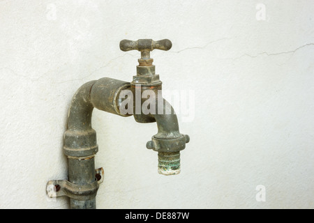 Old rusty water tap on cracked concrete wall Stock Photo