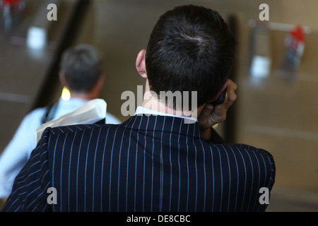 Man in pinstripe suit on phone at Canary Wharf Station in London's Docklands area Stock Photo
