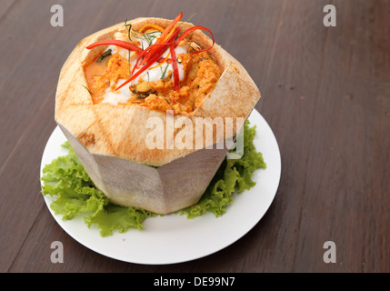 steamed fish and seafood with curry paste in coconut on table Stock Photo