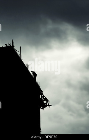 Construction site, silhouette of construction worker on the top of the building. Stock Photo