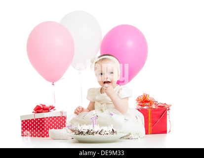 Smiling baby girl eating cake on first birthday Stock Photo