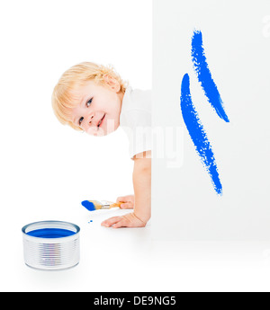 Baby boy with paint brush on all fours behind painted white wall Stock Photo