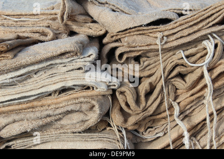 A pile of wheat colored burlap sacks with string ties Stock Photo
