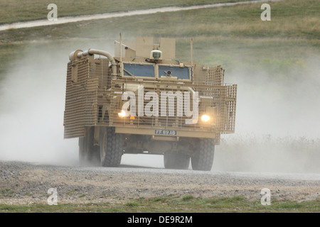 A British Army Mastiff patrol vehicle at speed creates a dust cloud on Salisbury Plain Stock Photo