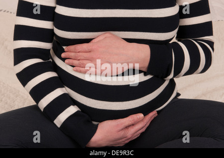 Cropped shot of a pregnant woman with her hands around her unborn baby bump Stock Photo