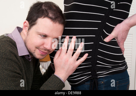 Pregnant woman with partner laying his head on her tummy and listening to the baby Stock Photo