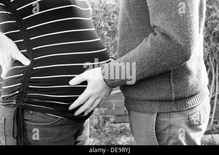 Black and white cropped shot of a pregnant woman with her partner touching baby bump Stock Photo