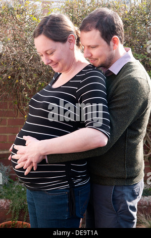 Pregnant woman and partner with their hands around her unborn baby bump Stock Photo