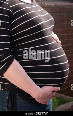 Cropped shot of a pregnant woman with her hands around her unborn baby bump Stock Photo