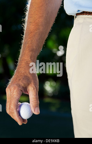Close up on male golfer's gloved hand holding a golf ball Stock Photo