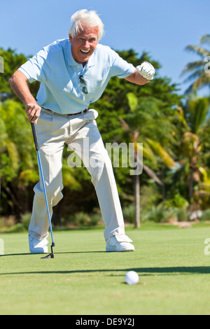 Happy senior man playing golf putting and celebrating a successful shot Stock Photo