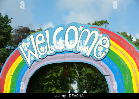 The cheery word welcome on a rainbow sign above a wooden arch at the Camp Bestival music festival entrance on a sunny day Stock Photo