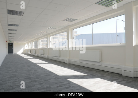an interior of and empty modern office space with grey carpet and white walls, looking out the windows Stock Photo