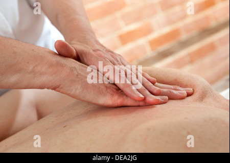 A pair of female Osteopaths hands giving treatment and massage to the back of another female Stock Photo