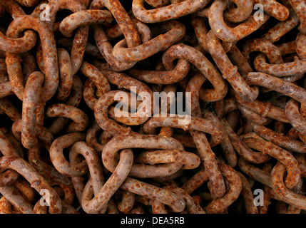 Rusted chains tangled as a background with a group of old textured [ iron metal links as an icon of a vintage prison chain or obsolete industry symbol of an ancient economy in decline. Stock Photo
