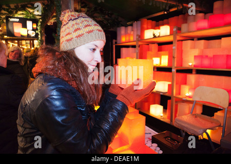 Young woman at the Christmas fair looking at candles, Esslingen, Baden Wurttemberg, Germany Stock Photo
