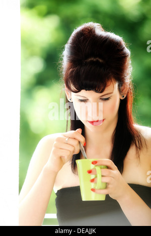 Beautiful Girl Retro Style Drinking Tea or Coffee. Cup of Hot Beverage green blured background Stock Photo