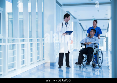 Smiling female nurse pushing and assisting patient in a wheelchair in ...