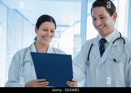 Two smiling doctors looking down at a medical record in the hospital Stock Photo