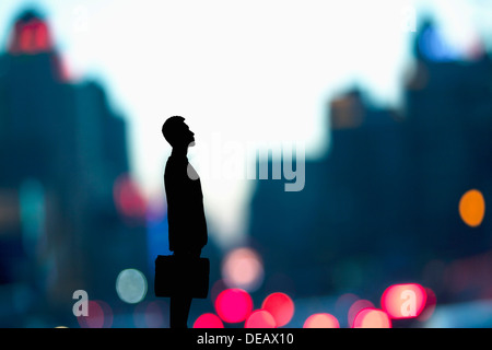 Silhouette of businessman holding a briefcase with blurred city lights behind him Stock Photo