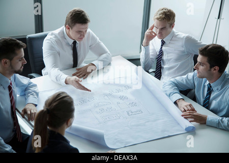 Five architects discussing and planning over a blueprint in the office Stock Photo
