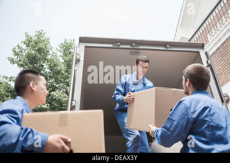 Movers unloading a moving van, passing a cardboard box Stock Photo