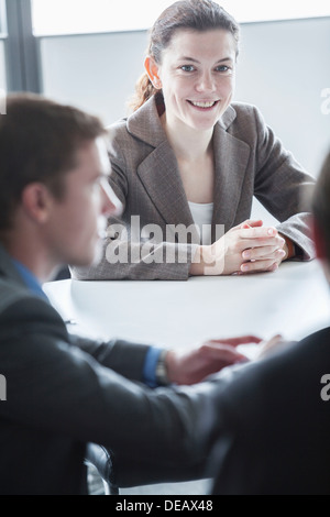 Three smiling business people sitting at a table and having a business meeting in the office Stock Photo