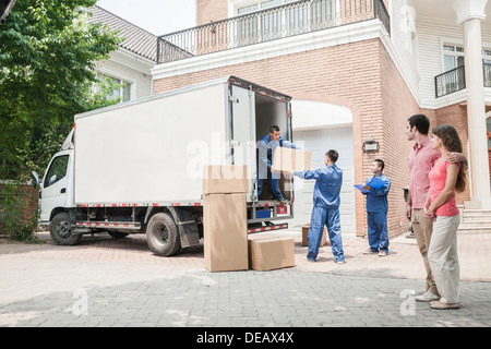 Young couple watching movers move boxes from the moving van Stock Photo