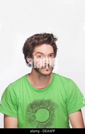 Young man with eyebrow raised looking at camera, studio shot Stock Photo