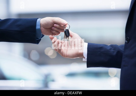 Car salesman handing over the keys for a new car to a young businessman, close-up Stock Photo