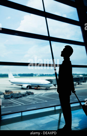 Silhouette of businessman waiting in the airport and looking out the window Stock Photo
