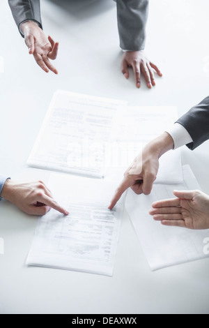 Four business people arguing and gesturing around a table during a business meeting, hands only Stock Photo