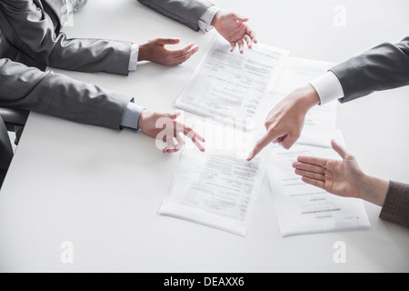 Four business people arguing and gesturing around a table during a business meeting, hands only Stock Photo