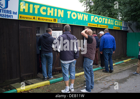 General view of spectators entering Hitchin Town FC on match day through old fashioned turnstiles. Stock Photo
