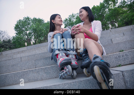 Two young friends with roller blades sitting and resting on concrete steps outdoors Stock Photo