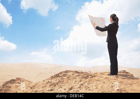 Young Businesswoman looking at a map in the middle of the desert Stock Photo
