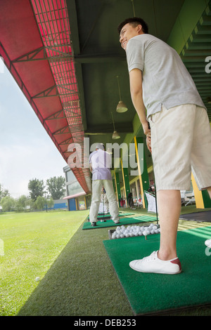 Young man swinging and hitting golf balls on the golf course Stock Photo