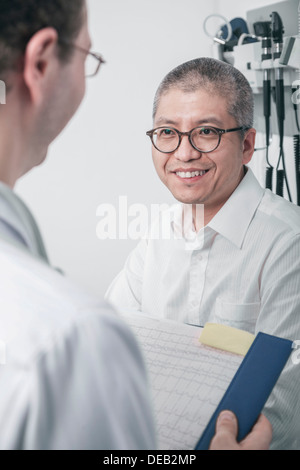 Doctor writing on medical chart with a smiling patient Stock Photo