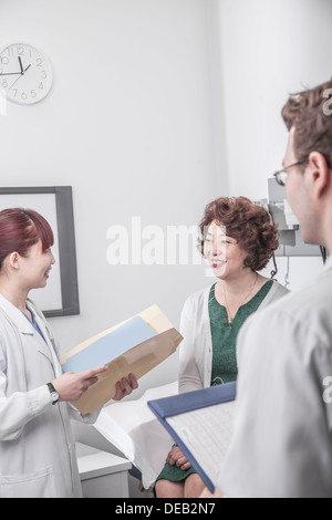 Two doctors holding medical charts discussing with a patient Stock Photo
