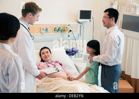 Family visiting the mother in the hospital, discussing with the doctor Stock Photo