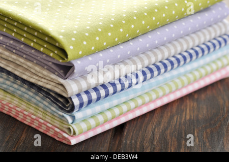 heap of fabrics on wooden table closeup Stock Photo