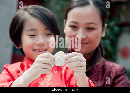 Mother and daughter making dumplings in traditional clothing, close up Stock Photo