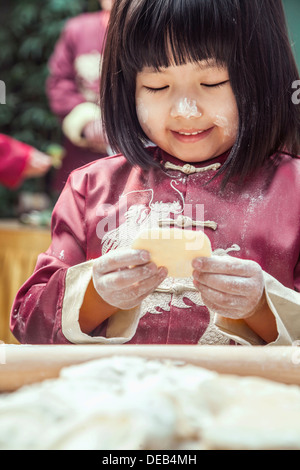 Portrait of little girl making dumplings in traditional clothing Stock Photo