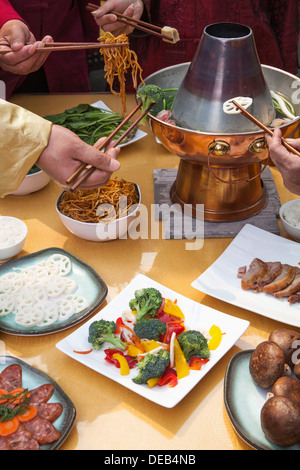 Family eating Chinese hot pot, hands only Stock Photo